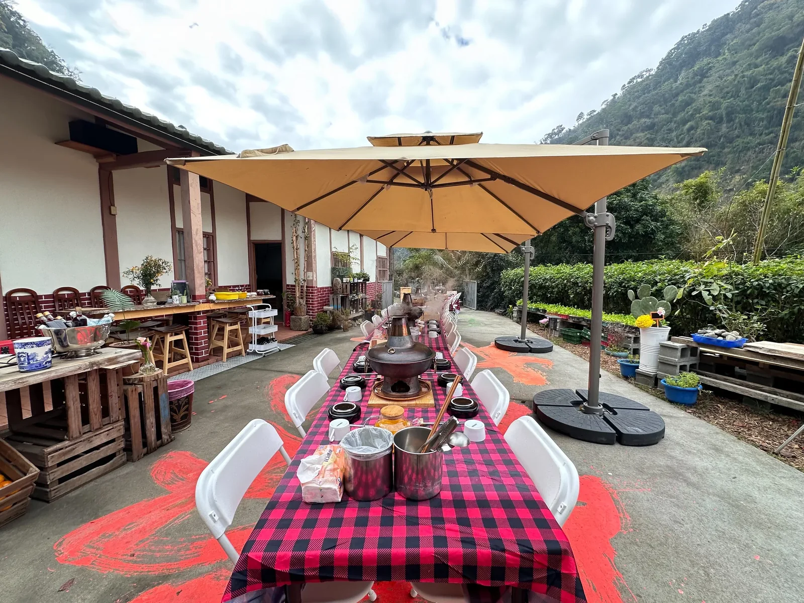 伍貳居所戶外長桌與遮陽傘,旁邊是老屋和山景
